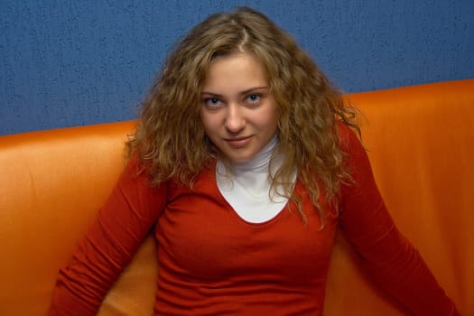 Portrait of the happy young girl sitting on a sofa