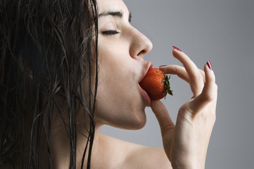 Topless caucasian woman biting a strawberry.