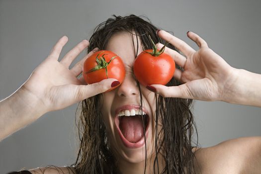 Caucasian woman with tomatoes covering her eyes.