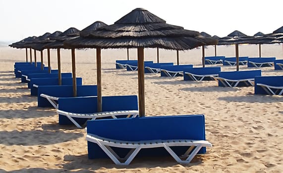 Sunshades and chaises long on an empty beach