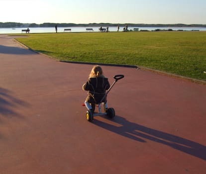 Child riding a tricycle near on a park.