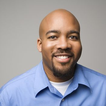 Portrait of African American man smiling against gray background.