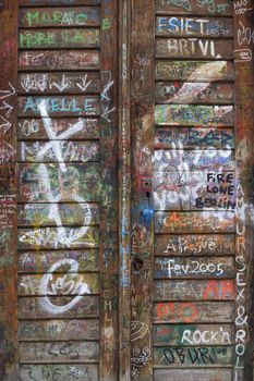 Layers and layers of graffiti and tagging vandalism on an old wooden door.