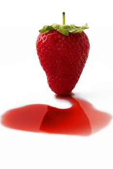 one strawberry on some red liquid in front of white background