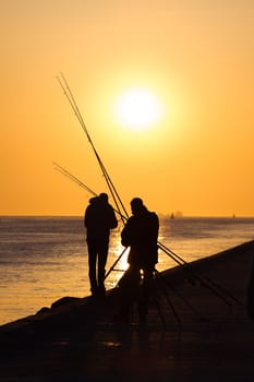 Fishermen on the pier - hazy and yellow sunset from volcanodust in the air