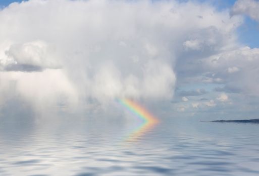 This image shows a rainbow and a big cloud over the ocean