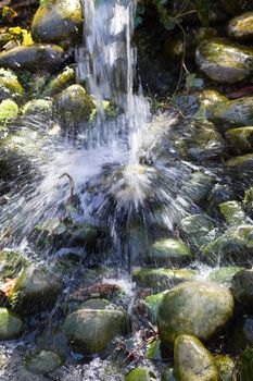 Water is splashing down on boulders from a waterfall