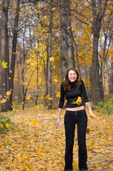 The young girl in autumn park during a leaf fall