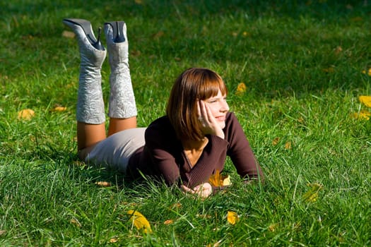 The young girl on green grass in autumn park