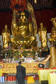 CHINA, NANTONG CITY - OCTOBER 15, 2008: prayer inside traditional Chinese temple with big buddha monument.