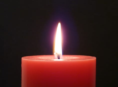 Red candle with flame on the black background