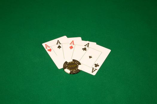 Casino chips on the green table and four aces