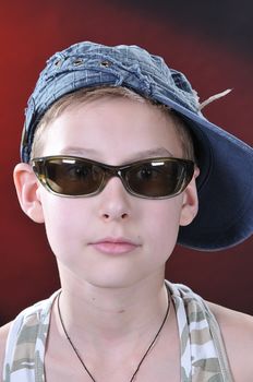 portrait of is 10-11 years old boy in a jean cap and sun glasses