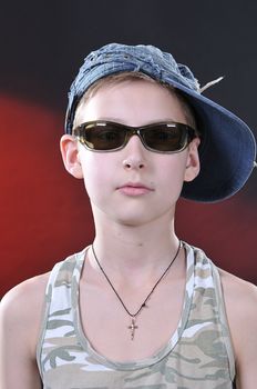 portrait of is 10-11 years old boy in a jean cap and sun glasses