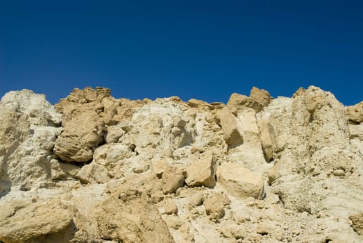 Some desert rocks in the front, a blue sky in the background. Picture taken with the Dead Sea, Israel
