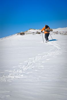 Single skier who is climping for the top. Woman mid 50's and a clear blue sky. Picture taken in Oppdal, Norway.