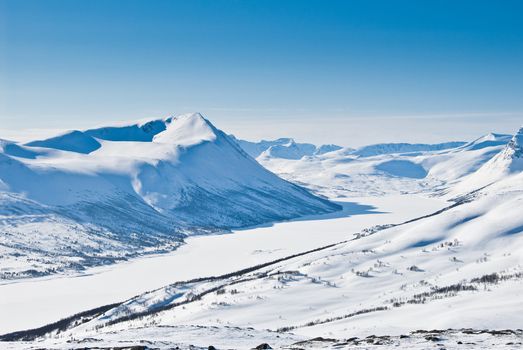 A snowy mountain landscape on a beautiful winter day. Picture taken in Oppdal, Norway, looking over Gjevillvatnet.