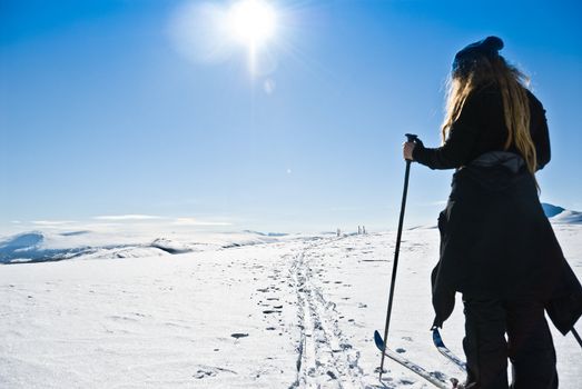 A single young lady (with dreads) cross cuntry skiing towards a ski camp. Beautiful winter day. Picture taken in Oppdal, Norway.