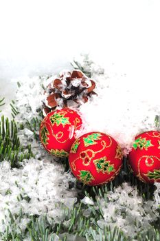 Christmas tree decorations on a pine tree branch with a pine cone