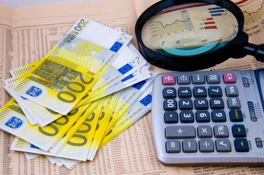 Closeup of euros, calculator and lens and background of newspaper with stock rate