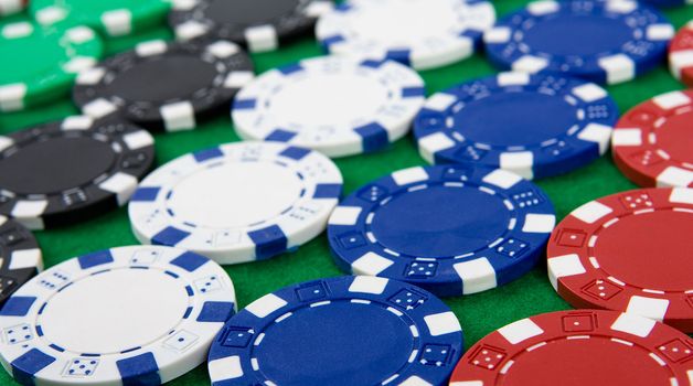 Background of different poker chips on green poker table.