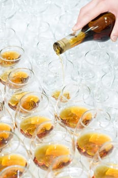 poring the brandy into many glasses, selective focus