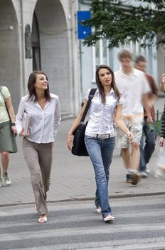 two young women going across the road in the center of town