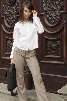 nice young teacher with glasses standing in front of an old fashion university door