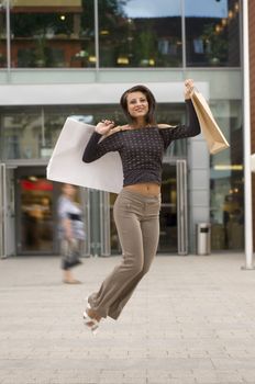 cute brunette jumping for joy in fronto of a commercial center after time for buy
