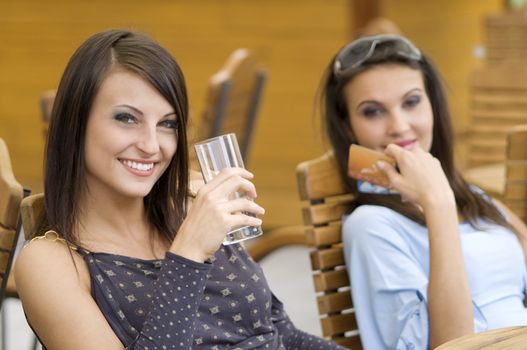 two girls relaxing in a pub after an hard day spent for shopping showing credit cards