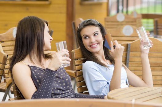 two girls relaxing in a pub after an hard day spent for shopping showi credit cards