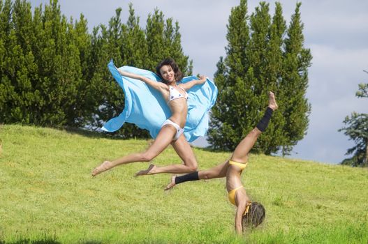 two girls jumping and stretching their body in a field