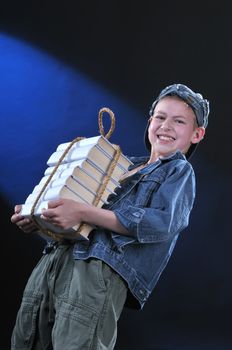 boy of ten years gets on the hip an exhausting load from the pile of books