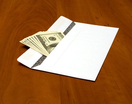 Dollar bills in a white envelope on the office desk.