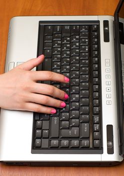 Female hand on the laptop keyboard.