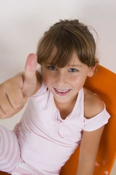 smiling cute little girl showing thumb's up hand gesture