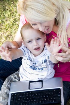 caring mother with laptop and her child sitting in her lap 