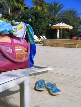beach wear, bag and sandals near swimming pool 