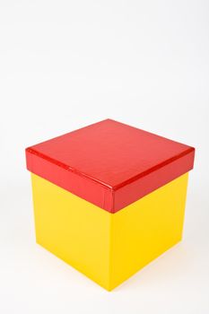 Shining yellow gift box with red cap isolated on white.