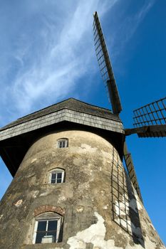 Traditional Old dutch windmill in Latvia against blue sky with white clouds