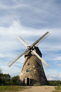 Traditional Old dutch windmill in Latvia against blue sky with white clouds