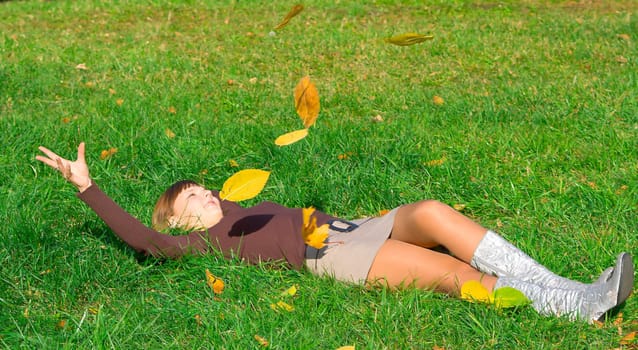 The young girl on green grass in autumn park