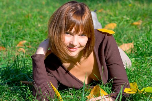 The happy girl on green grass in autumn park