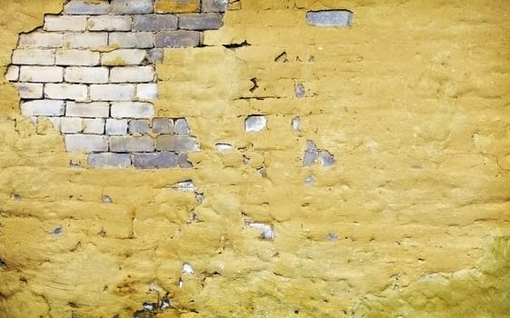 The brick yellow wall with broken plaster