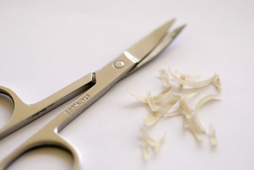 a pair nail scissors and some nail clippings