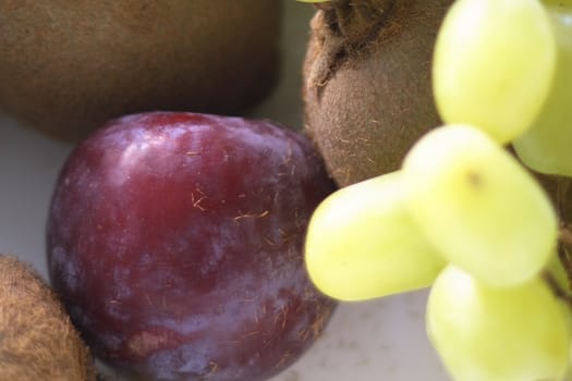 grapes out of  focus with  plums and kiwi in focus