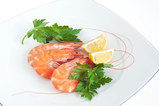 three raw prawns with lemon and parsley on a white plate isolated with clipping path
