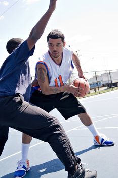 A young basketball player guarding his fierce opponent during a game of one on one at the park.