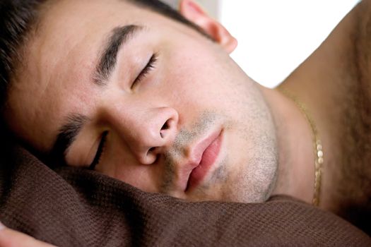 A young man is fast asleep in bed.