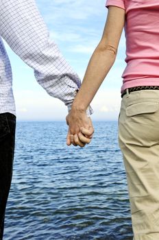 Mature romantic couple holding hands on the beach